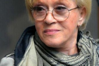 Пожилая женщина у окна с мягким светом на лице, спокойствие, размышление и ощущение внутреннего мира